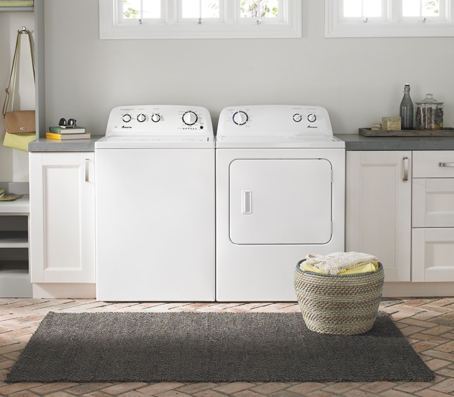 White washer and dryer set with laundry basket in front