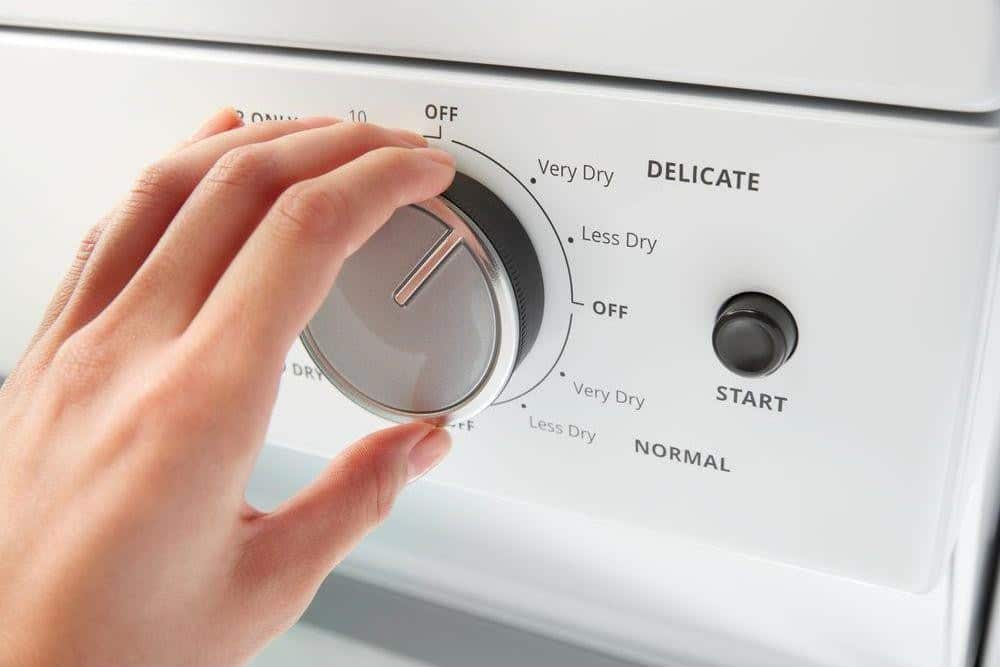 A hand changing the settings on a laundry machine
