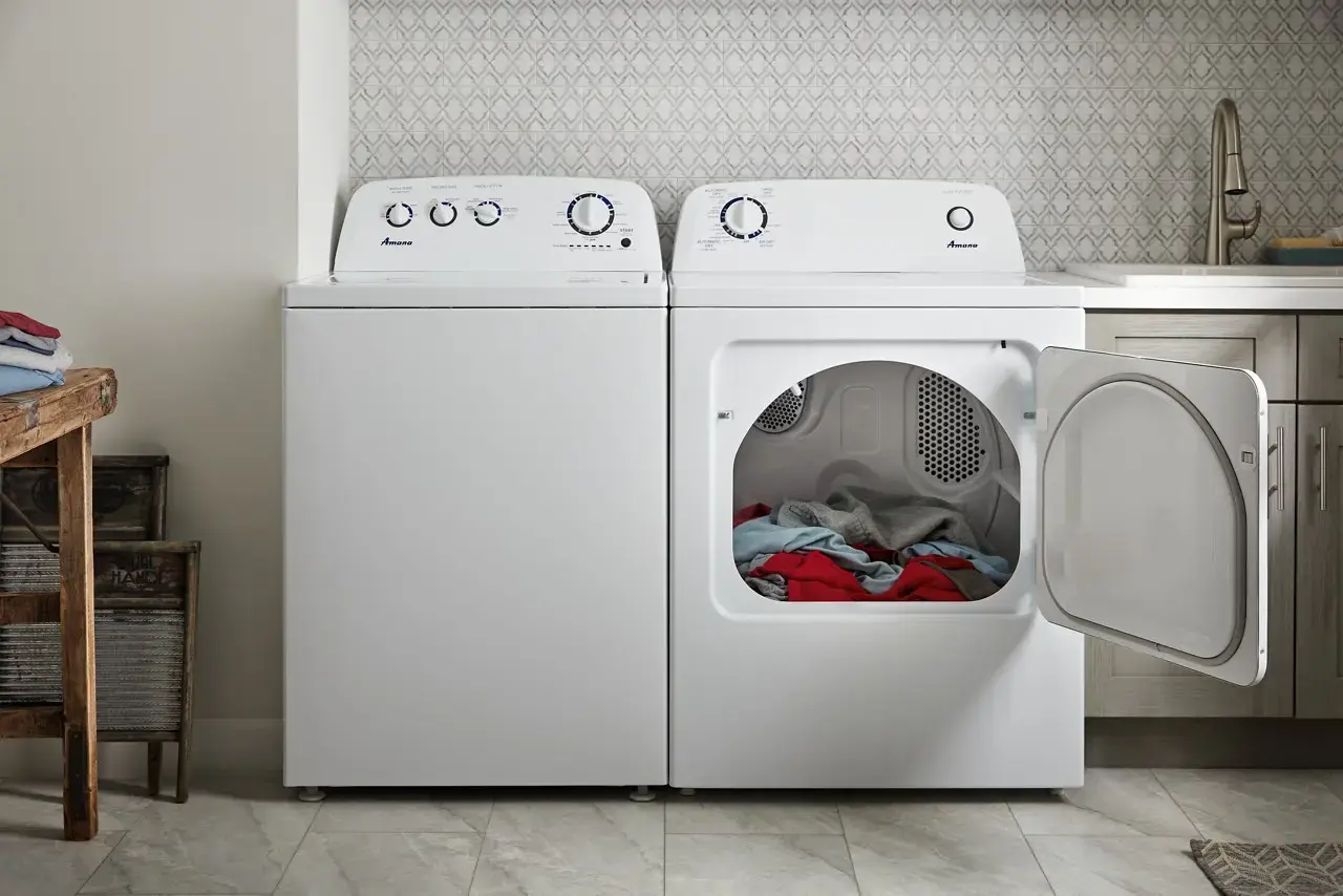 Two white laundry appliances side by side in a laundry room; the right unit is a front-loading dryer with its door open, revealing colorful clothes inside.