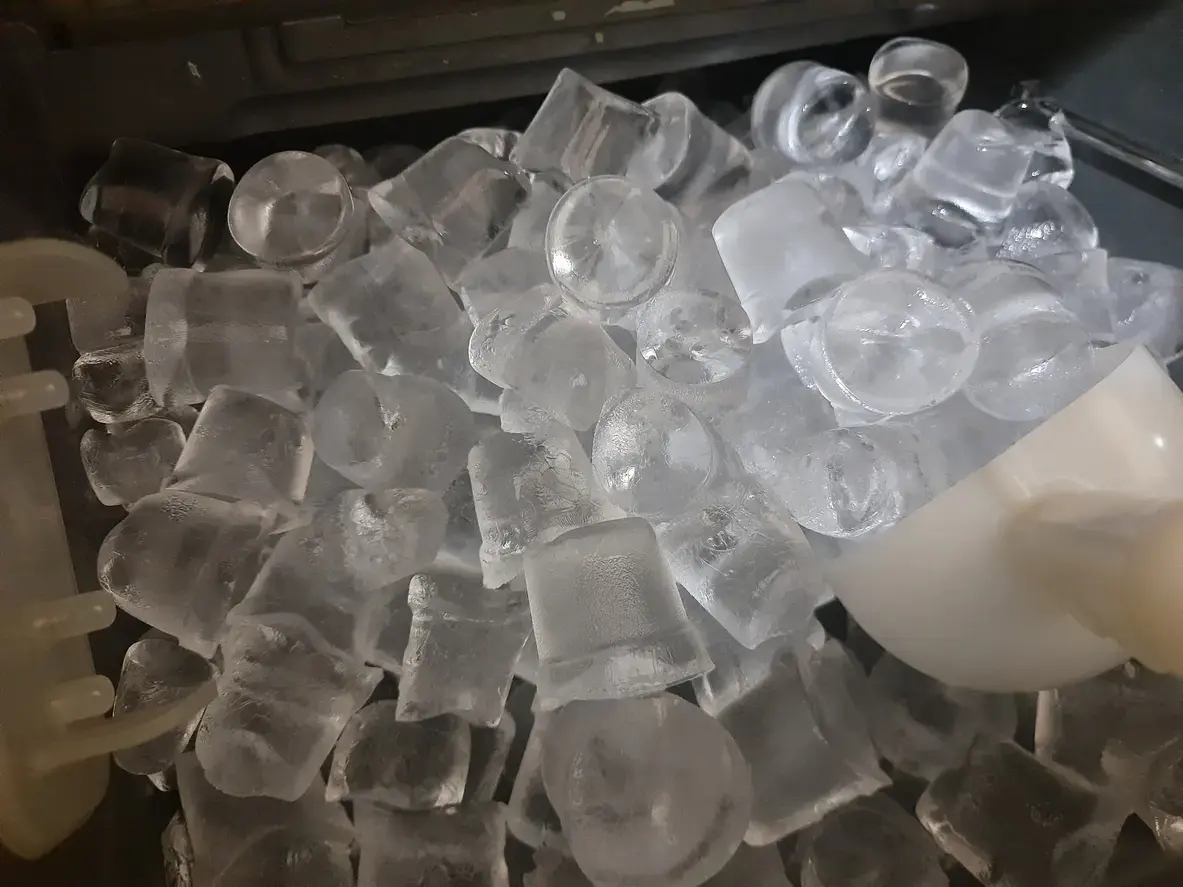 Pile of ice cubes in a freezer, clear and frosty and ready to chill drinks.