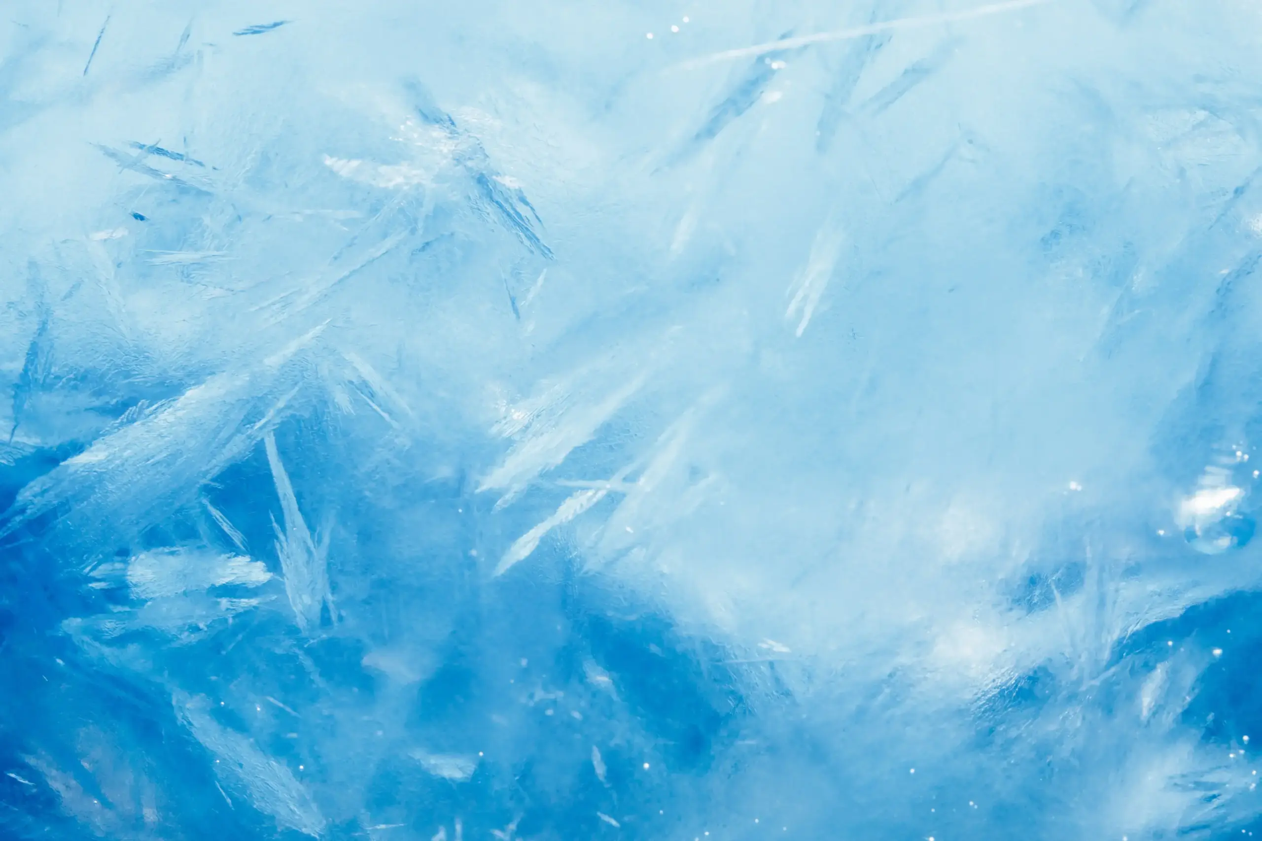 Close-up of blue ice with jagged, crystalline patterns and light reflections.